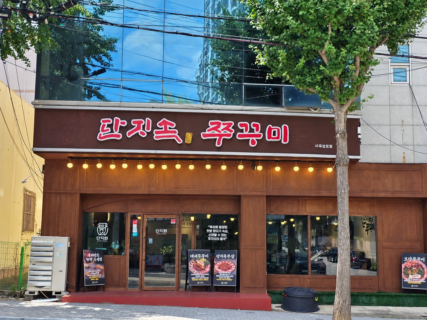 빨간 글자 간판 '단지속 쭈꾸미'가 달린 나무 외벽의 가게 정면